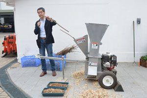 行政长官示範碎树枝机的运作。把树枝放进机器切碎後，能够循环再用於栽种植物，实行有机耕作。